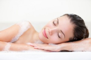 woman relaxing in bath with serene smile and closed eyes full of bath foam. Beautiful young multiracial Caucasian / Asian Chinese female model.
