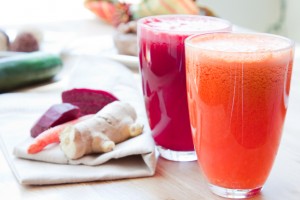 Two glasses of healthy juice - Beet, Apple, Carrot, Ginger and Orange, Apple, Pineapple. Ingredients in the background.